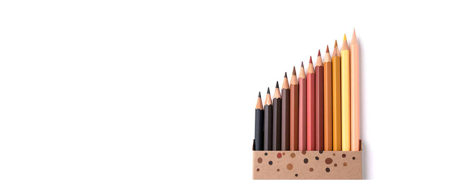 Aus einer geöffneten Buntstiftverpackung ragen 12 Buntstifte mit verschiedenen Hautfarben heraus