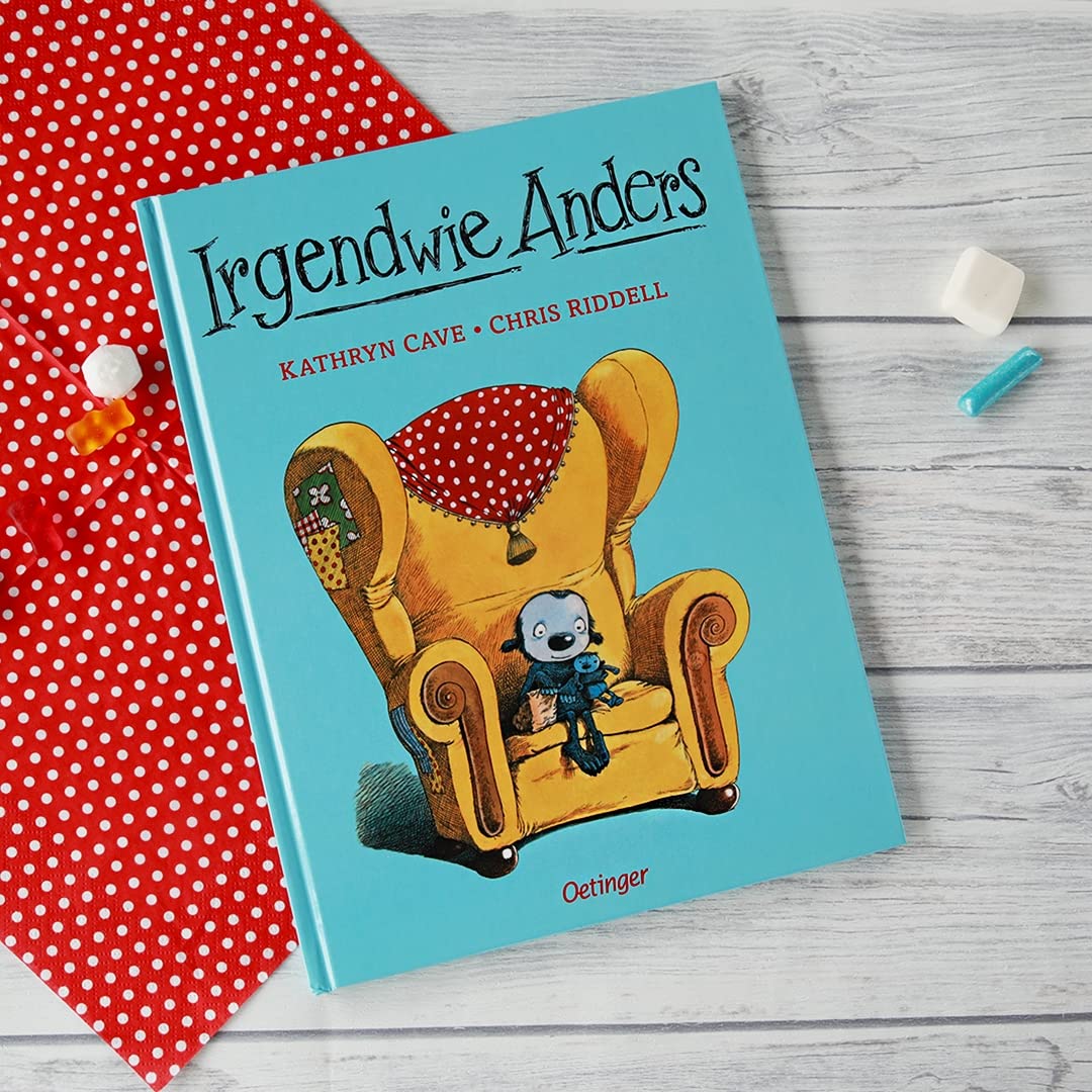 Buchcover von "Irgendwie Anders" als gebundene Ausgabe. Das Buch liegt auf   einem Holztisch, daneben liegt ein rotes Tuch und Süßigkeiten.