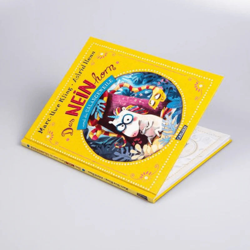 Kinderbuch "Das NEINhorn und die SchLANGEWEILE" leicht geöffnet von schräg oben. Von Marc-Uwe Kling und illustriert von Astrid Henn.