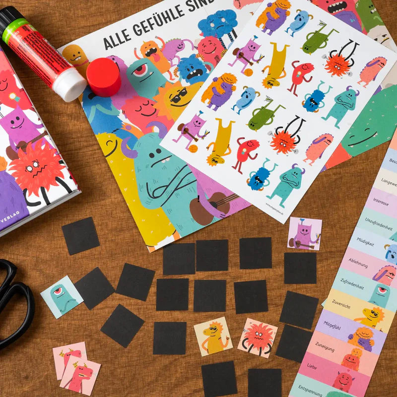Zwei Exemplare von "Ein gutes Gefühl 2" mit Stickerbögen und buntem Bastelzubehör auf dem Tisch.