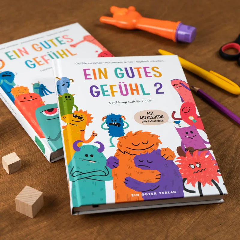 Kinderbuch "Ein gutes Gefühl 2" mit Bastelmaterial und Stickern auf einem Tisch.