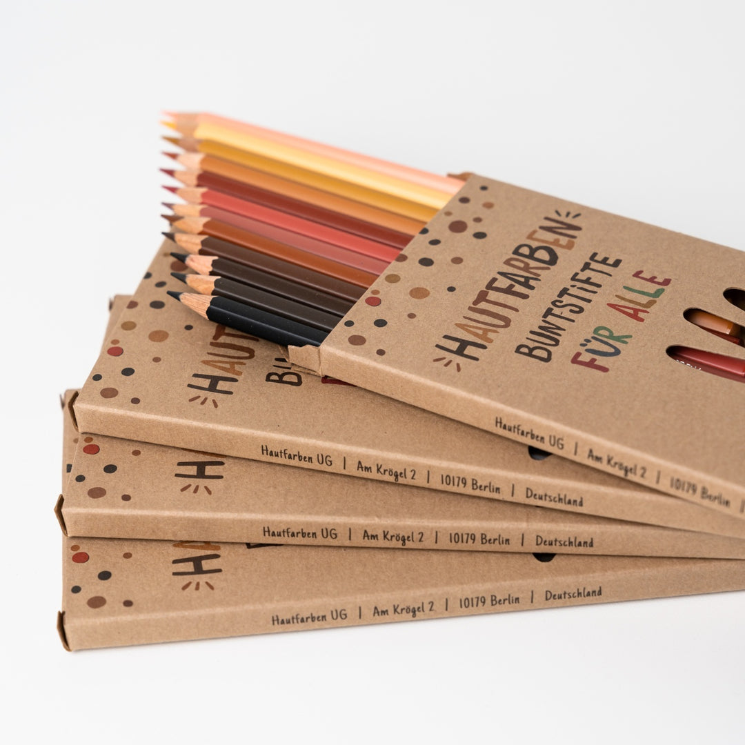 Stapel Hautfarben Buntstifte Sets für Kinder mit einer offenen Verpackung aus der Stifte heraus gucken
