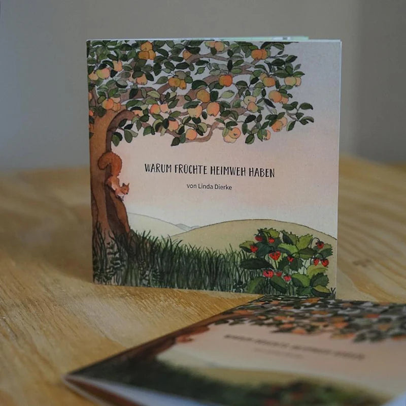 Kinderbuch "Warum Früchte Heimweh haben" steht auf einem Holztisch.