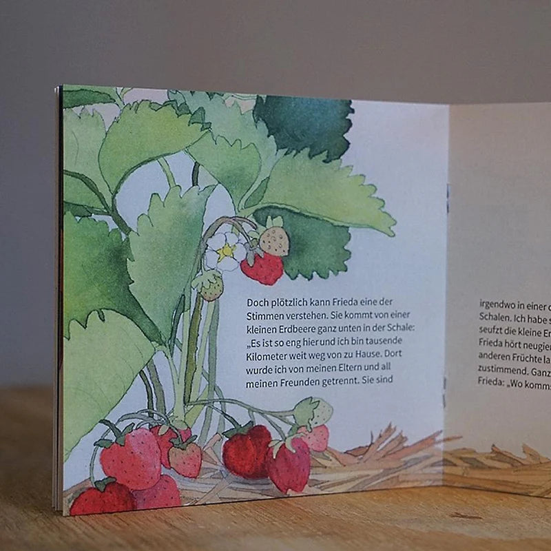Innenansicht aus dem Kinderbuch "Warum Früchte Heimweh haben" zeigt eine Illustration einer Erdbeerpflanze mit roten Früchten.